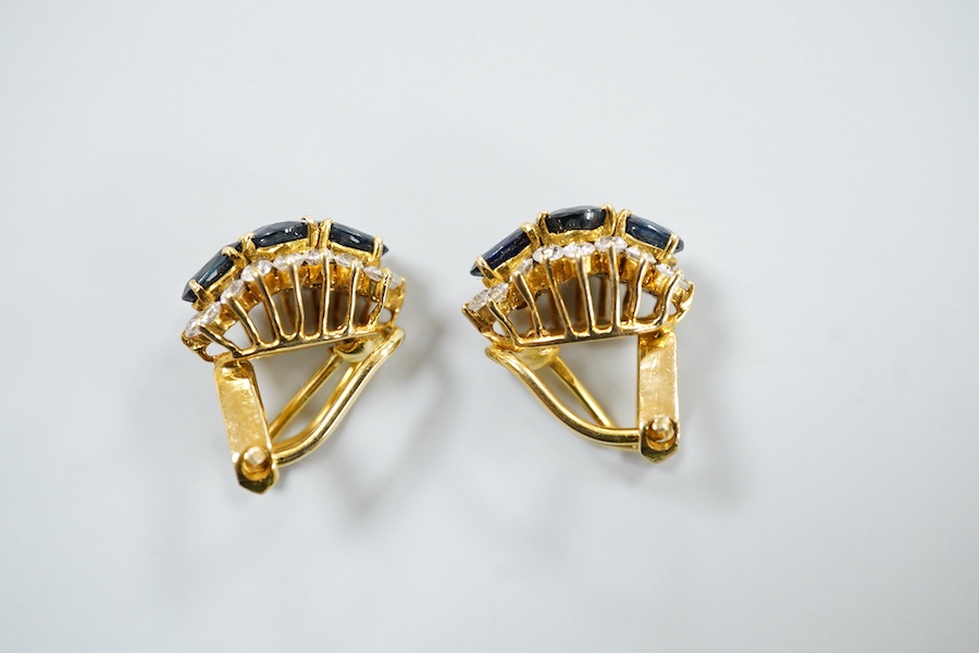 A pair of sapphire earrings, each set with three oval sapphires, within a border of brilliant-cut cubic zirconias, mounted in gold, length 1.4cm each, clip and retractable post fittings